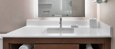 A modern bathroom with a white sink, a mirror, and wooden cabinets below.