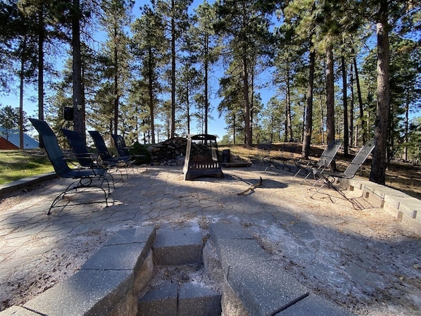 An outdoor seating area with metal chairs and a fire pit, surrounded by trees. - Diamond Jewel - Pool table, Fire Pit (Deadwood)