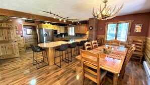 A spacious kitchen with a central island, wooden dining table, and chairs. - Diamond Jewel - Pool table, Fire Pit (Deadwood)