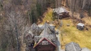 A cabin with a steep roof, surrounded by a forest.