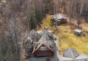 A cabin with a steep roof, surrounded by a forest.