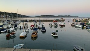 A marina with various boats docked, a calm water surface, and a distant shoreline. - Church Cottage (Bridport)