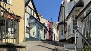 A stone staircase leading up to a street with traditional buildings, including a shop with a sign that reads "SEASALT CORNWALL." - Church Cottage (Bridport)