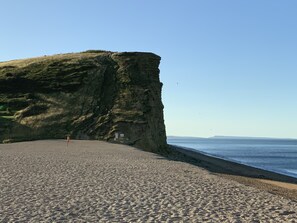 Een strand met een steile klif, een heldere lucht en een kalme zee.
