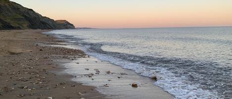 A beach with pebbles and a calm sea.