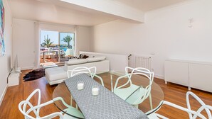 Una sala moderna con una mesa de comedor de vidrio, sillas blancas y un sofá blanco.