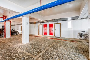 A parking garage with numbered parking spaces, a bicycle, and a red and white door.