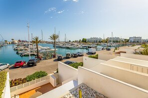 A marina with boats, a parking area, and buildings in the background.