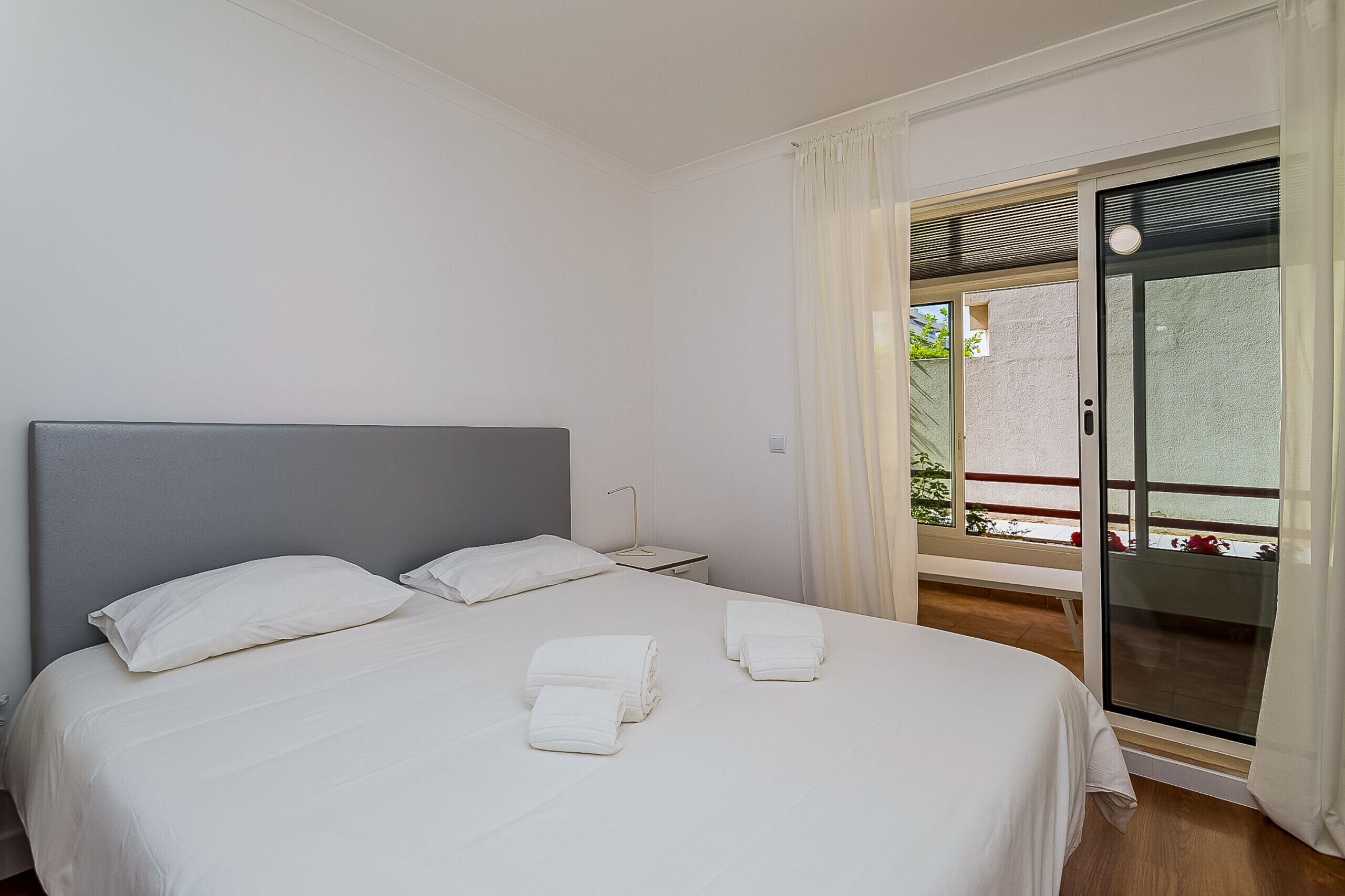 A hotel room with a bed, a nightstand, and a window with curtains.