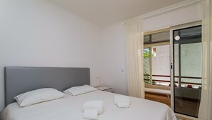 Habitación de hotel con cama, mesita de noche, ventana con cortinas y vistas al exterior.