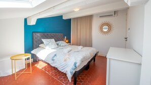 Une chambre à coucher avec un lit, une table de chevet, un miroir et une fenêtre de toit.