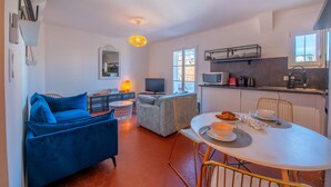 Un salon moderne avec un canapé bleu, un canapé gris et une table à manger pour quatre personnes.