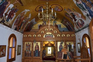 An ornate interior with religious artwork, a chandelier, and a central altar. - Lili Hotel (Malevizi)