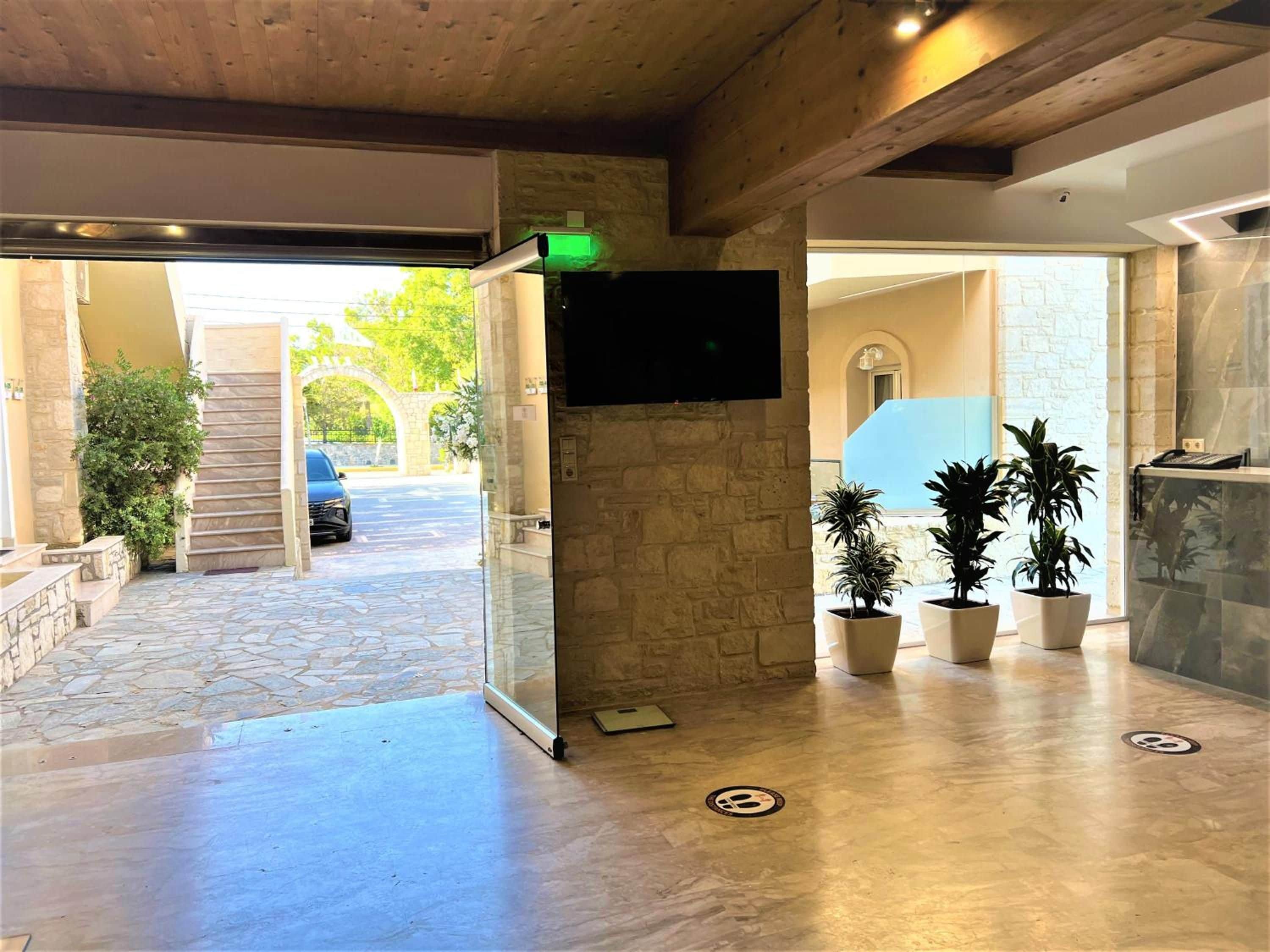 A reception area with a stone wall, a flat-screen TV mounted on the wall, and potted plants.