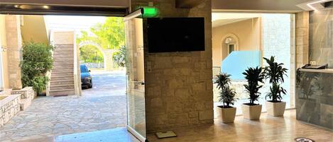 A reception area with a stone wall, a flat-screen TV mounted on the wall, and potted plants.