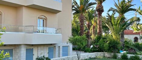 A multi-story building with balconies, a well-maintained lawn, and palm trees.