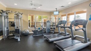 Une salle de sport équipée de tapis de course, d’une machine de musculation et d’un rameur.