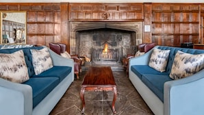 A traditional living room with two blue sofas, a wooden coffee table, and a stone fireplace.