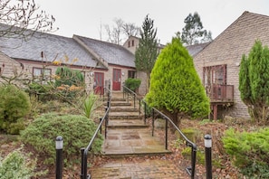 Step into a serene, historic setting surrounded by lush greenery and a traditional stone building.