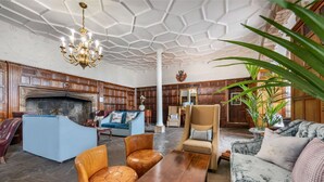 A spacious living room with a fireplace, leather sofas, a wooden coffee table, and a chandelier. - Modern 1-Bed Apartment | Near Lancaster | Sleeps 4 (Lancaster)