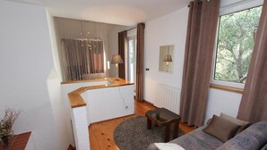 Een moderne woonkamer met een bank, een bijzettafeltje, een spiegel en uitzicht op het omliggende landschap door een raam.