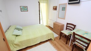 Un dormitorio con cama, cómoda, silla, mesa y televisor.