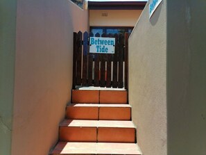Un conjunto de escaleras exteriores que conducen a una puerta con un cartel que dice 'Between Tide'.