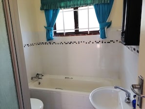 Un baño con bañera, lavamanos e inodoro.