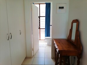 A hallway with a wooden dresser, a white toilet, and a blue curtain. - All the Tides - Hi Tide (Margate)