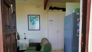 A compact room with a green sofa, a white cabinet, and a refrigerator. - All the Tides - Hi Tide (Margate)