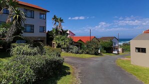 A residential street with houses, a clear sky, and a view of the ocean. - All the Tides - Rip Tide (Margate)