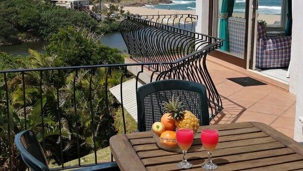 En balkon med et bord, stole og havudsigt.