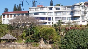 Un edifici residencial de diverses plantes amb teulada vermella, envoltat de vegetació exuberant i un petit pavelló.