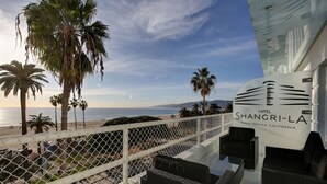 Uma varanda de hotel com vista para a praia e oceano.