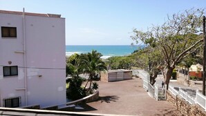 A residential area with a white building, a paved pathway, and a view of the sea. - Claridges 404 (Margate)