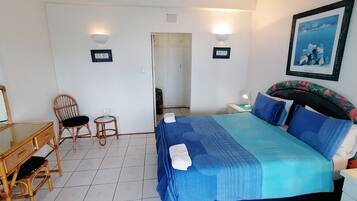 A bedroom with a bed, a desk, two chairs, a small table, and a door.