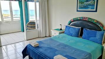 A bedroom with a bed, a chair, a nightstand, and a window with curtains.