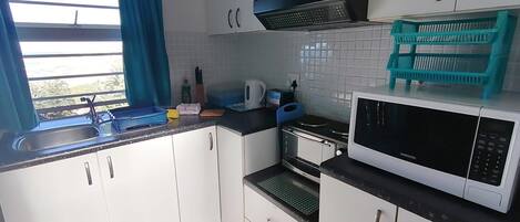 A kitchen with white cabinets, a microwave, a stove, and a sink.