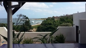 A balcony with a view of the sea, a sandy beach, and a hillside with buildings. - Rosscarbery 3 (Margate)