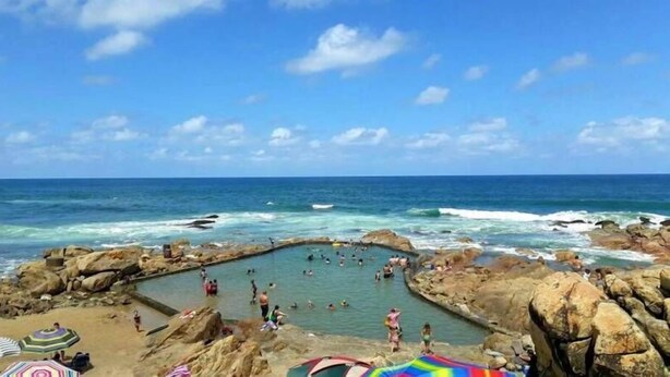 A rocky beach with a natural swimming area surrounded by large rocks and a clear blue sky. - Rosscarbery 3 (Margate)