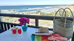 A table with a view of the ocean, a vase of flowers, two glasses of red drink, a straw hat, and a woven basket. - Rosscarbery 5 (Margate)