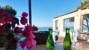 A table with two bottles of BERNIN Classic sparkling wine, a glass, and a vase with pink flowers. - Southern Comfort - On the Pool (Margate)