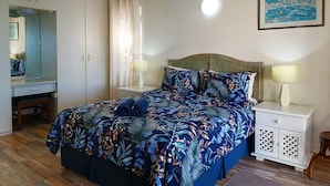 A bedroom with a bed, nightstands, a mirror, and a painting on the wall. - Southern Comfort - On the Pool (Margate)