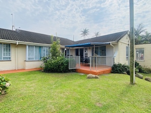 A two-story house with a covered porch and a small garden area.
