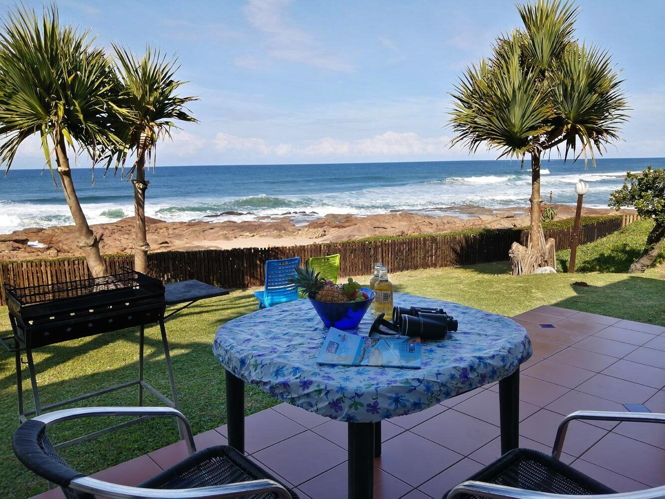 A patio with a round table, chairs, and a grill.