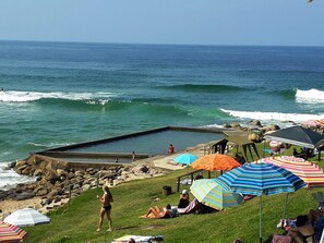 A beach with a pool, umbrellas, and people relaxing. - Southern Comfort - Periwinkle (Margate)