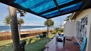 Un pati amb vistes a l'oceà, una taula amb cadires i una petita zona de jardí.