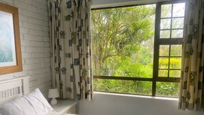 A bedroom with a bed, pillows, a bedside table with a lamp, and a window with curtains. - Weavers Nest (Margate)