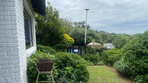 A garden with a white brick wall, a wooden ladder, and a metal grill. - Weavers Nest (Margate)