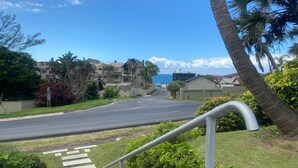 A residential street with a clear view of the ocean, palm trees, and a modern building with balconies. - Weavers Nest (Margate)